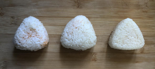 Photo shows three onigiri. One hand rolled, one plastic wrap rolled, and one made in an onigiri mold.