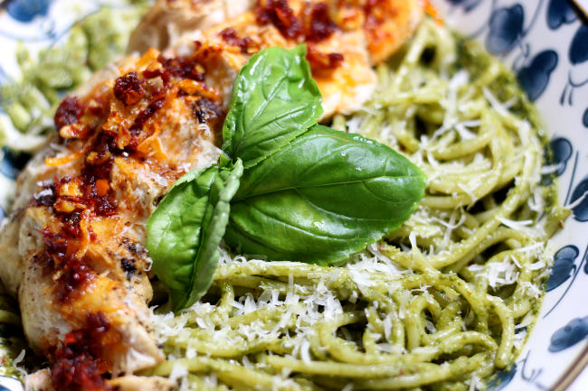 Photo of chili crisp pesto pasta up close, focusing on the basil leaf garnish in the middle.