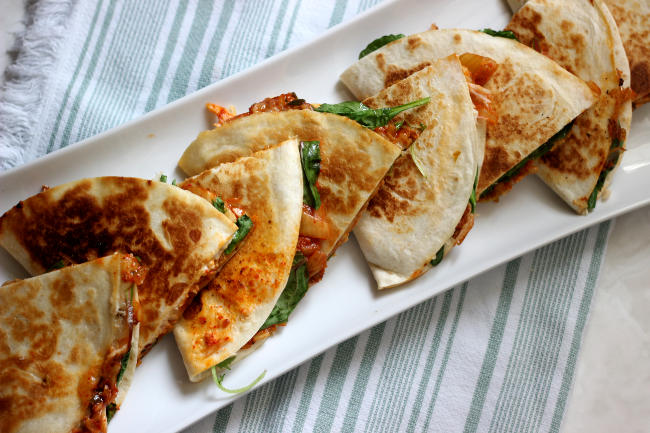 Kimchi quesadillas cut in half and arranged in a line.