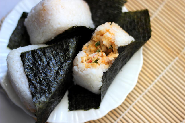 Three crab onigiri, one has a bit taken out of it.